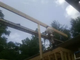 Carpenter setting a ridge beam over a new addition frame — Ice Dam Removal by Roofing Brothers in Quinby