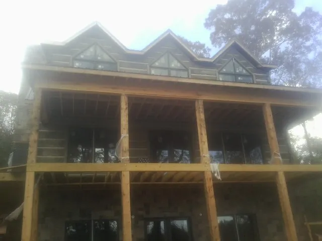 Dormers and porch framing on a large log home under construction — Roof Coating work by our crew in Quinby