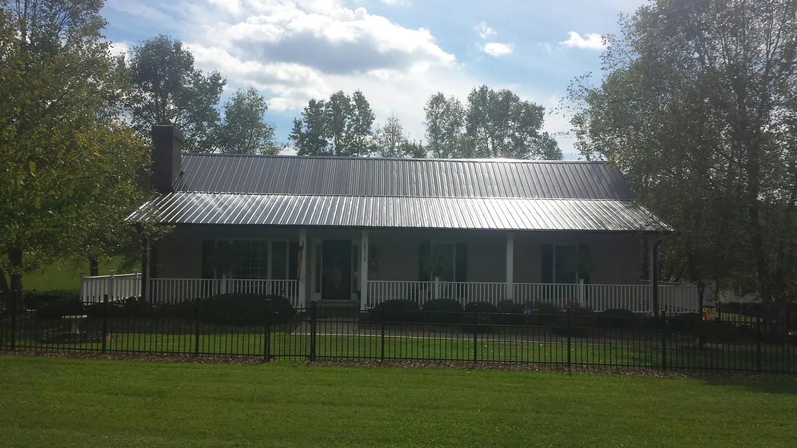 Gray metal roof on a brick ranch with a full width front porch — Gutter Guard Installation work by our crew in Quinby