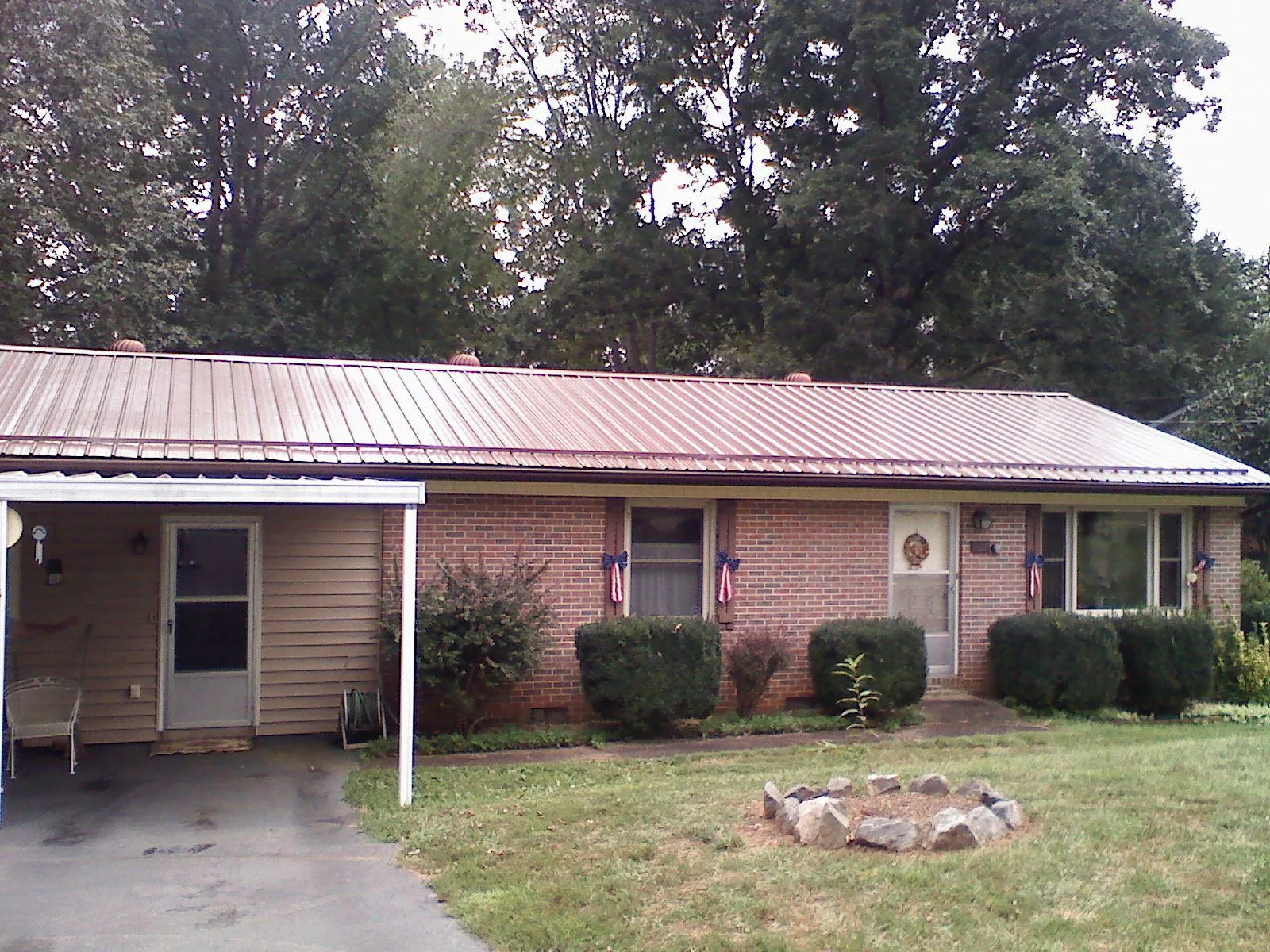 Bronze metal roof and carport on a brick ranch home — Roof Repair work by our crew in Quinby