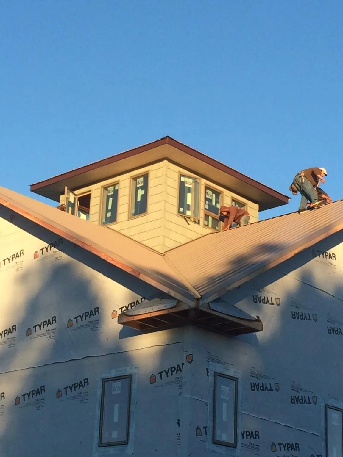 Roofers working around a rooftop cupola on a new metal roof at sunset — Roof Waterproofing in Quinby by Roofing Brothers